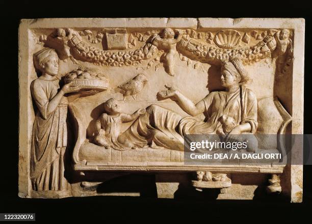 Roman civilization, 2nd century A.D. Relief portraying a woman and a child at a feast: a maidservant bringing a plate laden with food.
