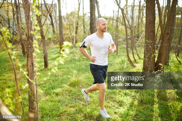 ein mann mittleren alters geht im wald joggen, dehnt sich und macht fitnesstraining - 2k resolution stock-fotos und bilder