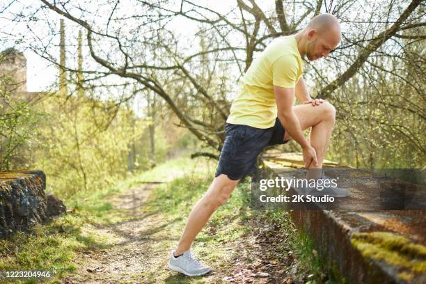 ein mann mittleren alters geht im wald joggen, dehnt sich und macht fitnesstraining - 2k resolution stock-fotos und bilder