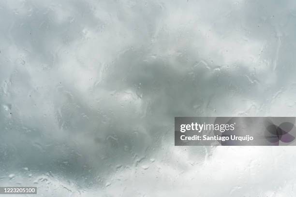 rain drops on a window with storm cloud behind - s rain or shine stockfoto's en -beelden