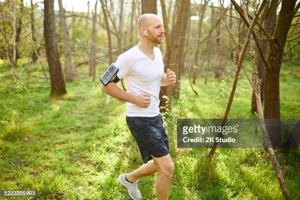 ein mann mittleren alters geht im wald joggen, dehnt sich und macht fitnesstraining - 2k resolution stock-fotos und bilder