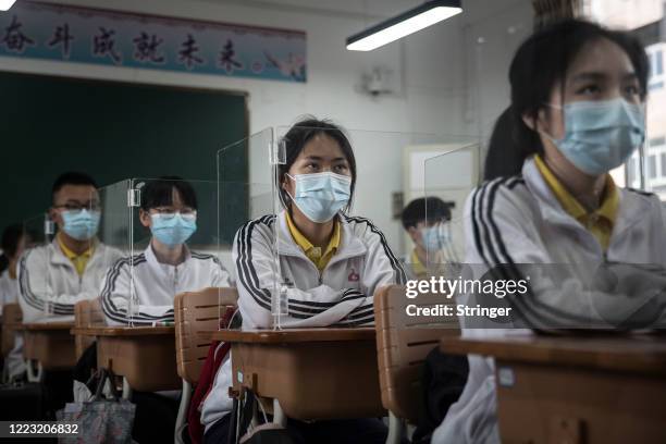 Senior students study in a classroom with transparent boards placed on each desk to separate each other as a precautionary measure against the spread...