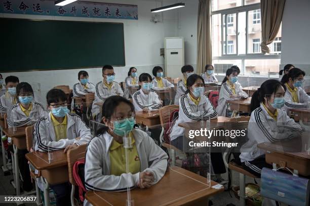 Senior students study in a classroom with transparent boards placed on each desk to separate each other as a precautionary measure against the spread...