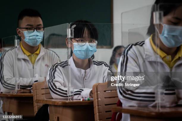 Senior students study in a classroom with transparent boards placed on each desk to separate each other as a precautionary measure against the spead...