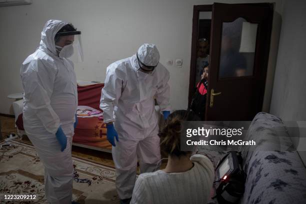 Family members watch on as paramedics from Turkey’s 112 Emergency Healthcare services tend to a patient with COVID-19 symptoms at her home in the...