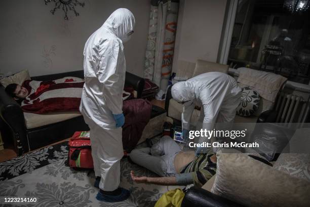 Family member watches on as paramedics from Turkey’s 112 Emergency Healthcare services tend to a patient with COVID-19 symptoms at his home in the...