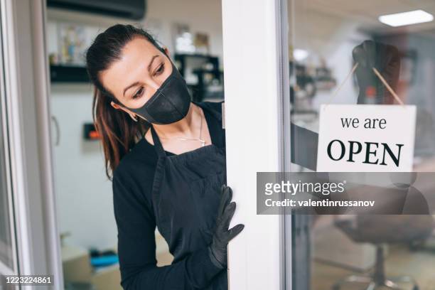 happy business owner hanging an open sign during covid-19 - opening event stock pictures, royalty-free photos & images