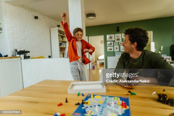 father and son playing board game ludo at home - game night stock pictures, royalty-free photos & images