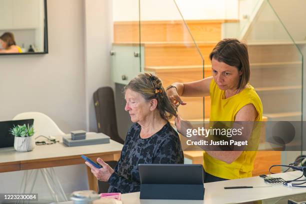 Woman cutting her senior mother's hair