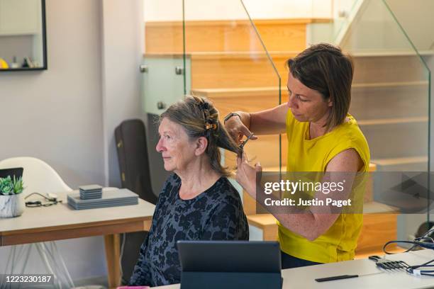 woman cutting her senior mother's hair - forbici per parrucchieri foto e immagini stock