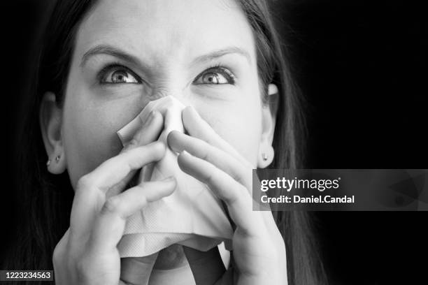 young woman blowing her nose with a tissue - closeup of a hispanic woman sneezing foto e immagini stock