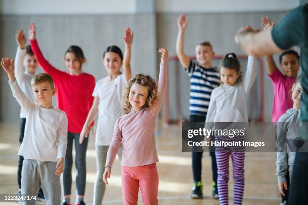 group of pupils with unrecognizable teacher exercising indoors in gym class. - skolidrott bildbanksfoton och bilder