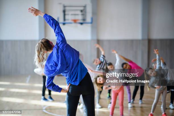 group of pupils with teacher exercising indoors in gym class. - sportunterricht stock-fotos und bilder