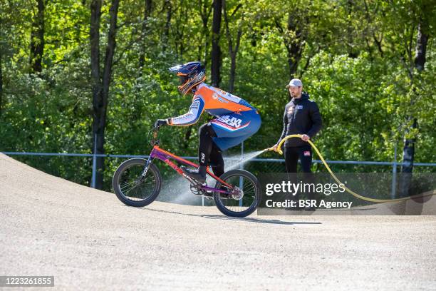 Joris Harmsen in action while head coach Raymon van der Biezen is spraying the track with water at the Dutch top BMX riders first training at...