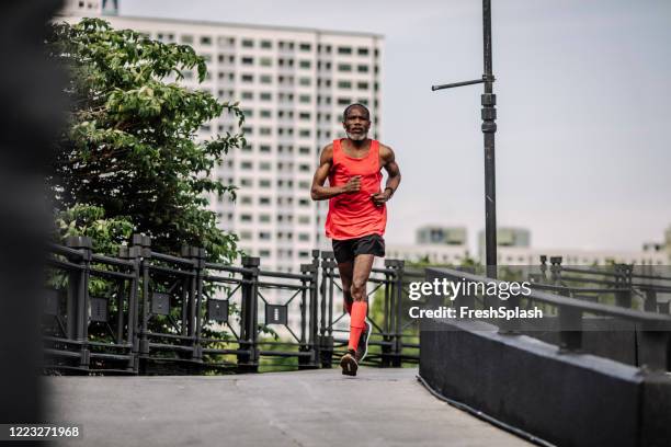 erholung in den 50er jahren: senior man running in the city - center athlete stock-fotos und bilder