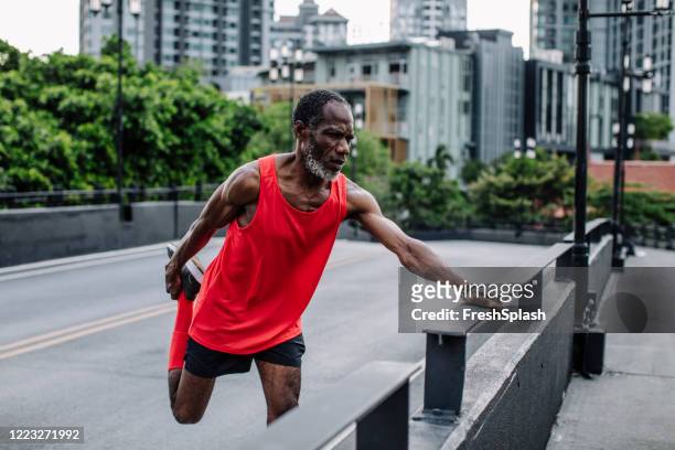 homem afro-americano sênior em red running roupas esportivas aquecendo antes do treino - legs black stockings - fotografias e filmes do acervo