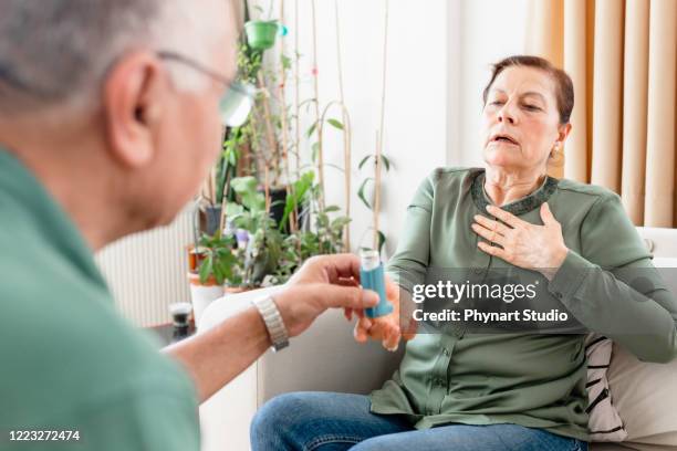 an older woman with asthma problems uses an asthma inhaler - copd stock pictures, royalty-free photos & images