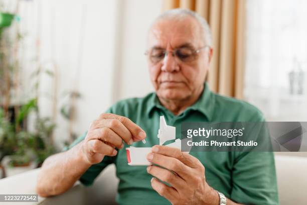 een oudere man met astmaproblemen gebruikt een astma-inhalator. - copd patient stockfoto's en -beelden