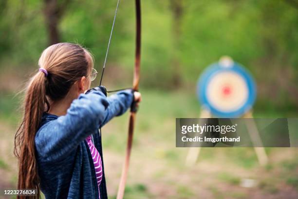tonårsflicka skjuter båge mot mål i skogen - girl pointing bildbanksfoton och bilder