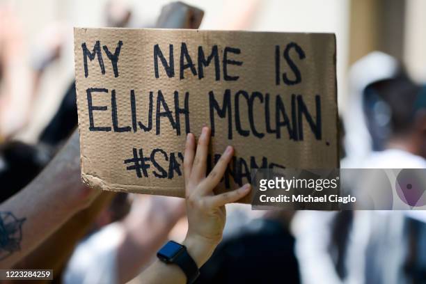 Woman holds up a sign as people rally outside the Aurora Police Department Headquarters to demand justice for Elijah McClain on June 27, 2020 in...