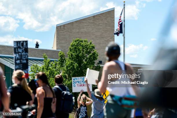 Police officer watches over protesters as they march outside the Aurora Police Department Headquarters to demand justice for Elijah McClain on June...