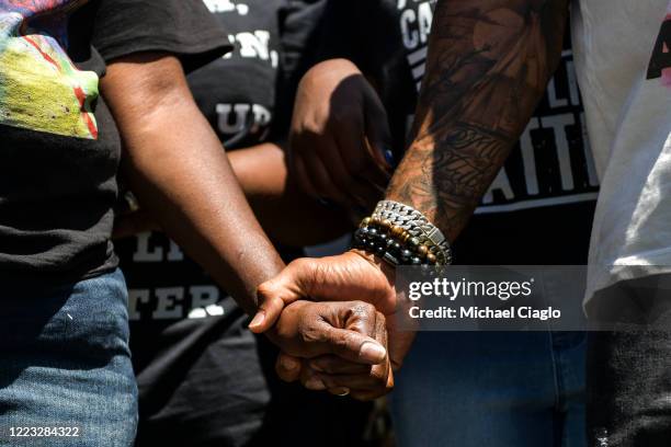 Elijah McClain's mother, Sheneen McClain, left, holds the hand of a protester as they rally outside the Aurora Police Department Headquarters to...