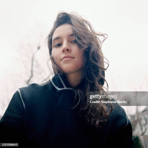 Young woman smiling looking at camera with cloudy sky behind her