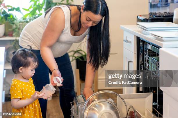 pregnant mother doing chores with toddler - loading dishwasher stock pictures, royalty-free photos & images