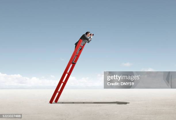 businessman on leaning ladder looks through binoculars - see through stock pictures, royalty-free photos & images