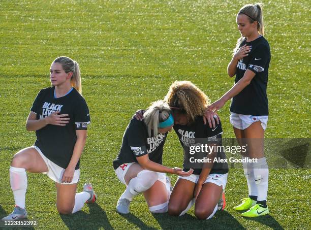 Julie Ertz and Rachel Hill hold Casey Short of the Chicago Red Stars kneel during the playing of the national anthem prior to a game against the...