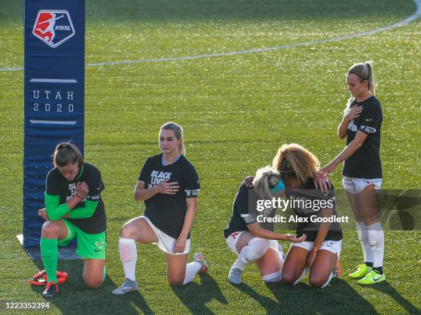 Julie Ertz and Rachel Hill hold Casey Short of the Chicago Red Stars kneel during the playing of the national anthem prior to a game against the...