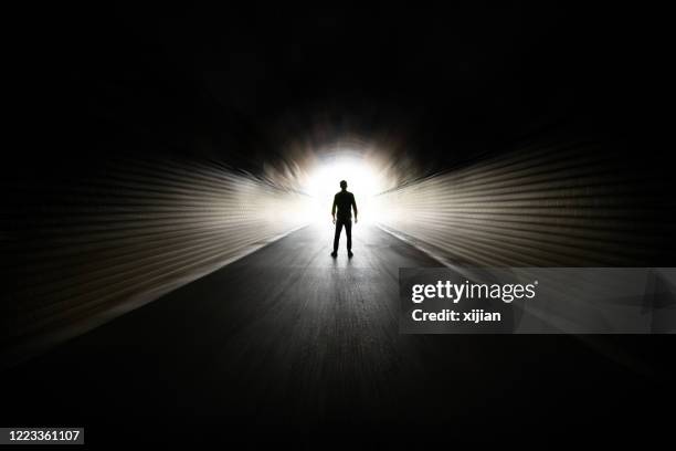 homme marchant dans le tunnel foncé - fin photos et images de collection