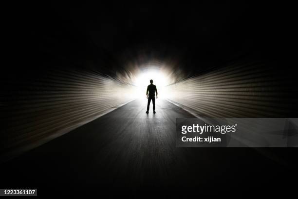 mens die in donkere tunnel loopt - het einde stockfoto's en -beelden