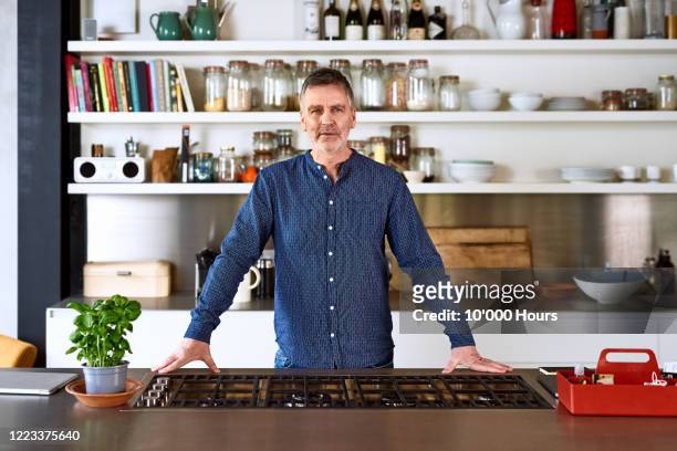 portrait of mature man in kitchen - burner stove top stock pictures, royalty-free photos & images
