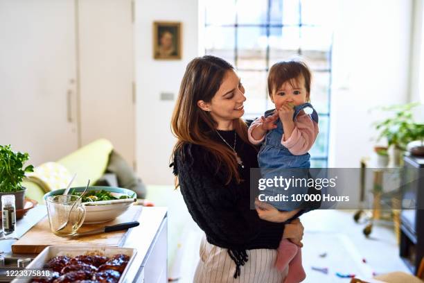 mother holding daughter in kitchen - raising baby stock-fotos und bilder