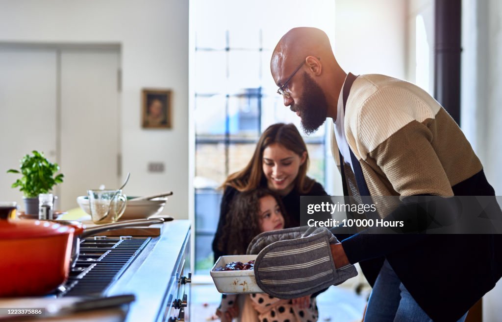 Father making dinner with mother and daughter at home