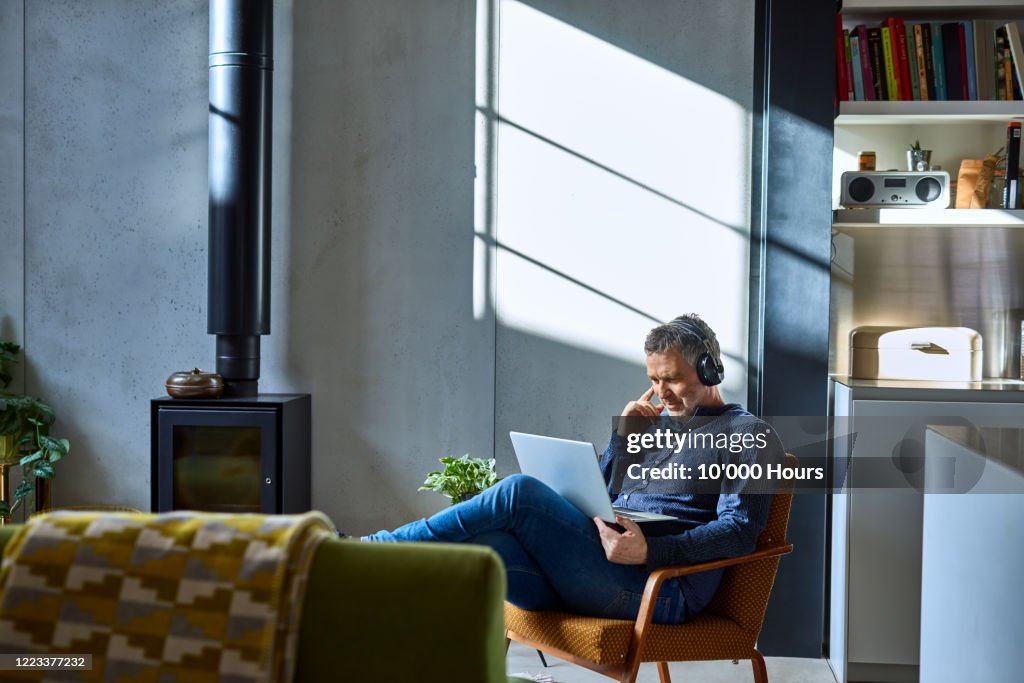 Mature man listening to music on laptop