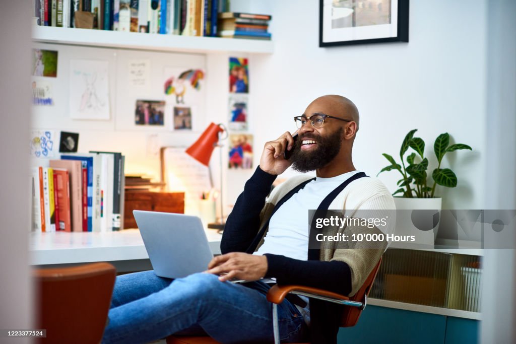 Cheerful businessman working from home on phone