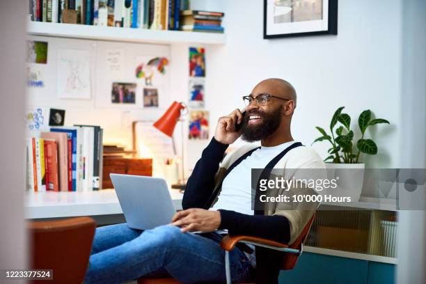 cheerful businessman working from home on phone - zwarte kleur stockfoto's en -beelden