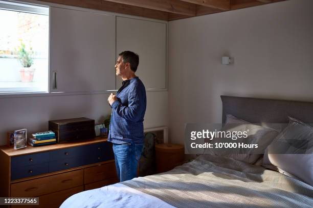mature man getting ready in bedroom - one mature man only foto e immagini stock