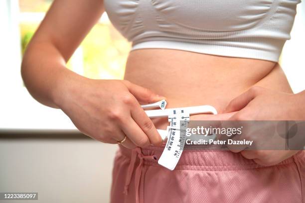 teenager using a skin fold caliper to calculate her bmi - skin fold calliper - fotografias e filmes do acervo