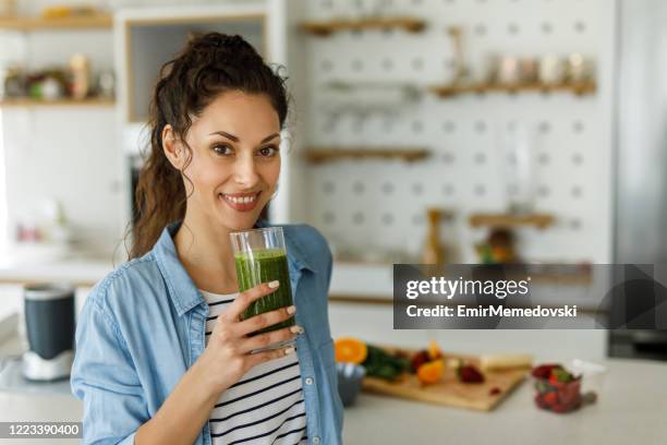 weibliche halten glas grünen spinat detox smoothie - drinking juice stock-fotos und bilder