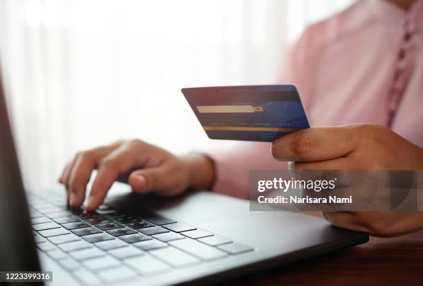 hands holding a credit card and using the laptop for online shopping and online payment via the internet. technology concept. - credit score stock pictures, royalty-free photos & images