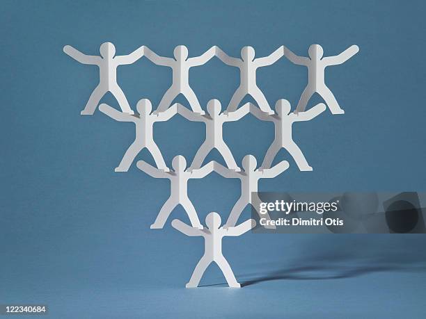 rows of paper cut-out men balancing on one - trust photos et images de collection