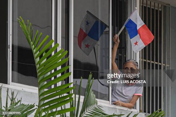 Woman waves a Panamanian flag as the police cheers up the neighbourhood with dances and songs during a lockdown to help contain the COVID-19 novel...