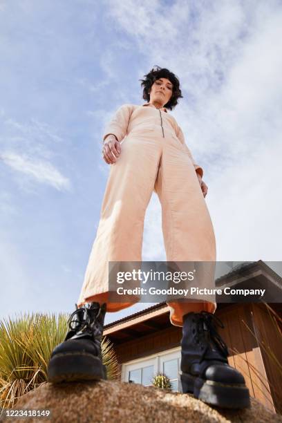 stylish young woman standing on a rock outside - low angle view stock pictures, royalty-free photos & images