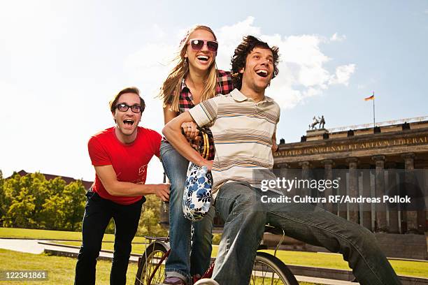 friends riding bike together in park - andreas pollok stock-fotos und bilder