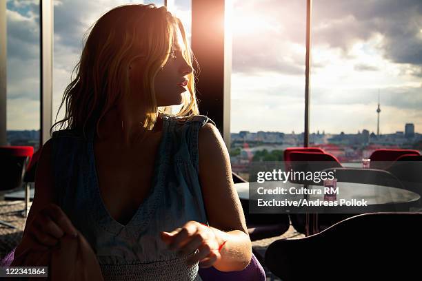 woman sitting in cafe at sunset - andreas pollok stock-fotos und bilder