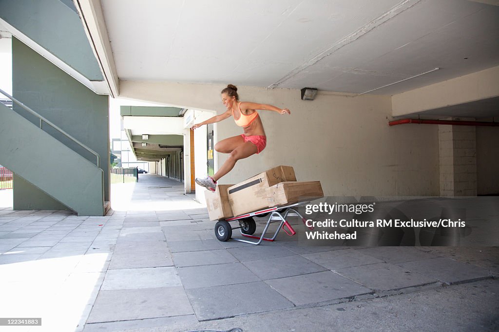 Runner jumping over boxes on city street