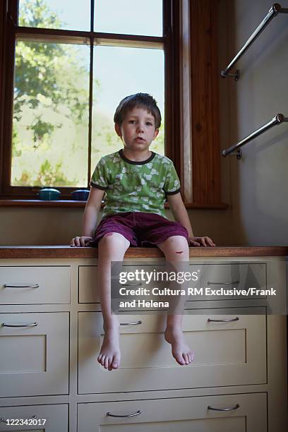 boy sitting on kitchen counter - scraped knee stock pictures, royalty-free photos & images